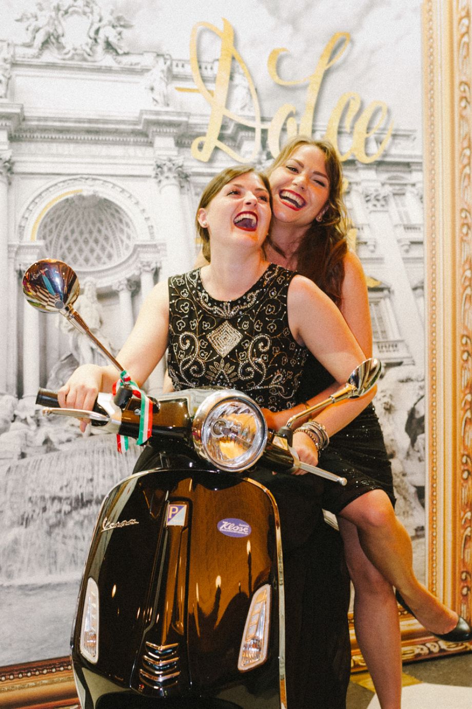 Zwei Damen posieren auf einer Vespa auf dem Ball des Weines